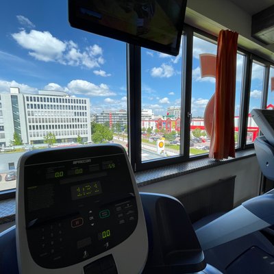 Auf dem Bild ist der Cardio‑Bereich des Fitness Express Vaihingen zu sehen. Mehrere Laufbänder stehen nebeneinander in Reihen. Die Geräte sind modern und in einem gut beleuchteten, großzügigen Raum angeordnet. Durch Fenster fällt Tageslicht in den Trainingsbereich, wodurch die Umgebung freundlich und einladend wirkt. Das Bild zeigt den Blick aus dem Fenster auf einem der Laufbänder stehend.